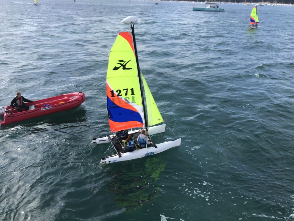 Inès et ses amies naviguent avec joie à bord du catamaran Hobie Cat Catsy, découvrant l'aventure de la voile dans un cadre magnifique en mer.